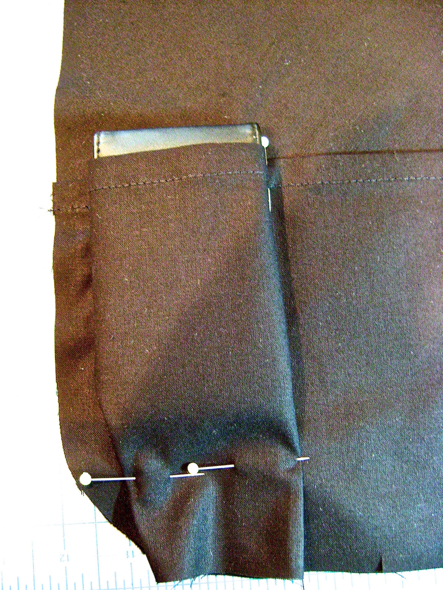 step 5 - Position your first item. Drape the fabric over it and pin the pocket to the lining on the right side of this space. Don’t make it too snug. 