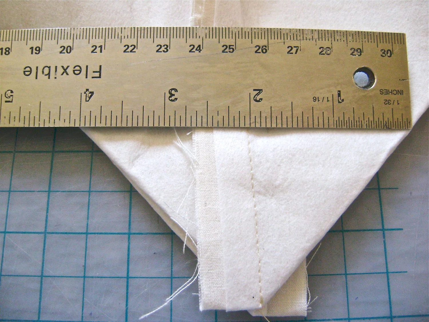 step 6 - Place a ruler across the layers, aligning the 2” mark with the seam stitching. There should be 2” of fabric to the left and right of center.