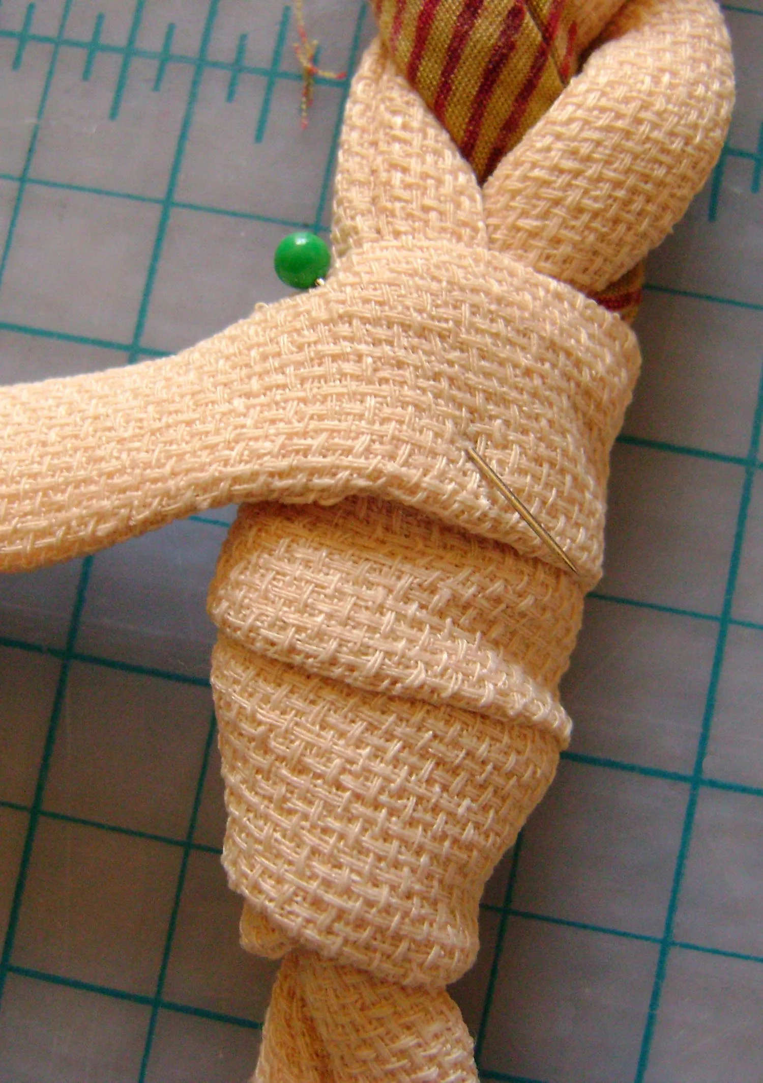 step 4 - Hide the connection and raw edges by sewing a 3/4” wide by 6” long flat piece of fabric to the loop slightly below the point where it connects to the braid. Wrap around, angling upward until the raw edges are covered. Pin in place.