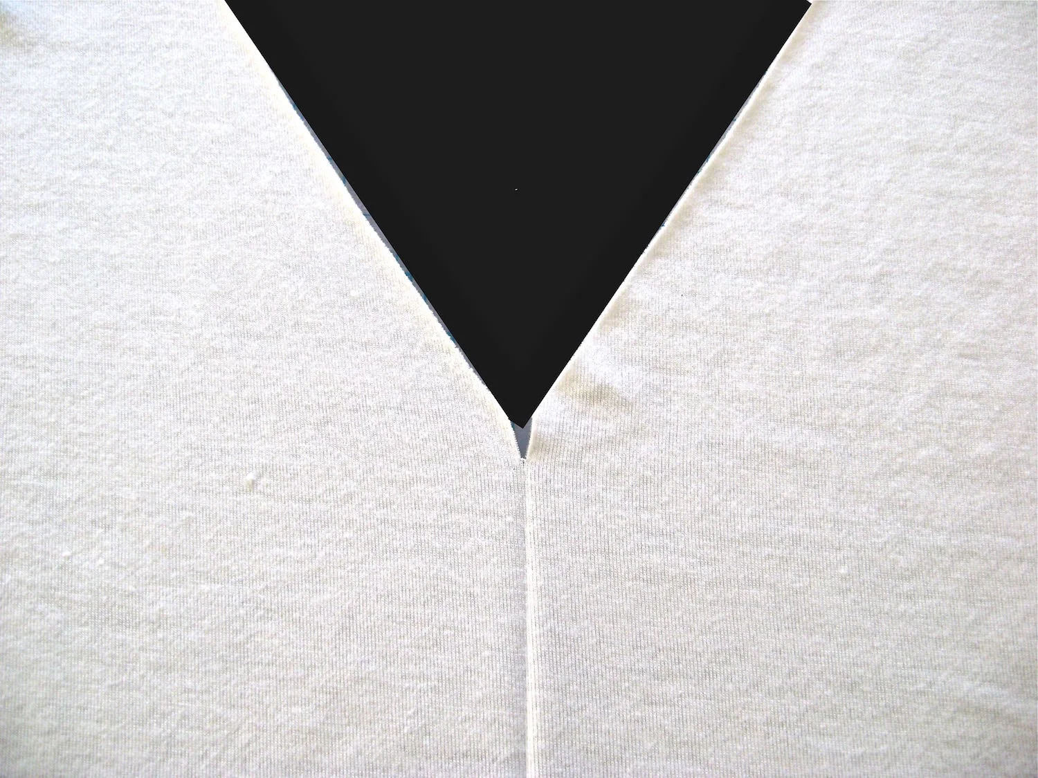 step 1 - Fold the shirt front in the center and press in a soft crease extending about 4 inches down from the point of the “V”. Snip a ½” opening in the point of the “V”.
