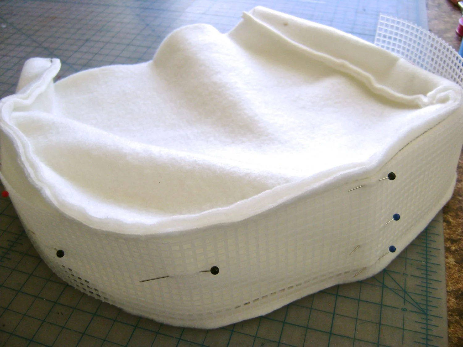 step 21 - Assemble the fleece padding by sewing the front and back to the side and bottom piece. Match the center of the mesh piece to the center bottom of the fleece’s wrong side. Stitch the mesh to the fleece. This can be carefully done on the machine with a stitch length to match the mesh or by hand. 