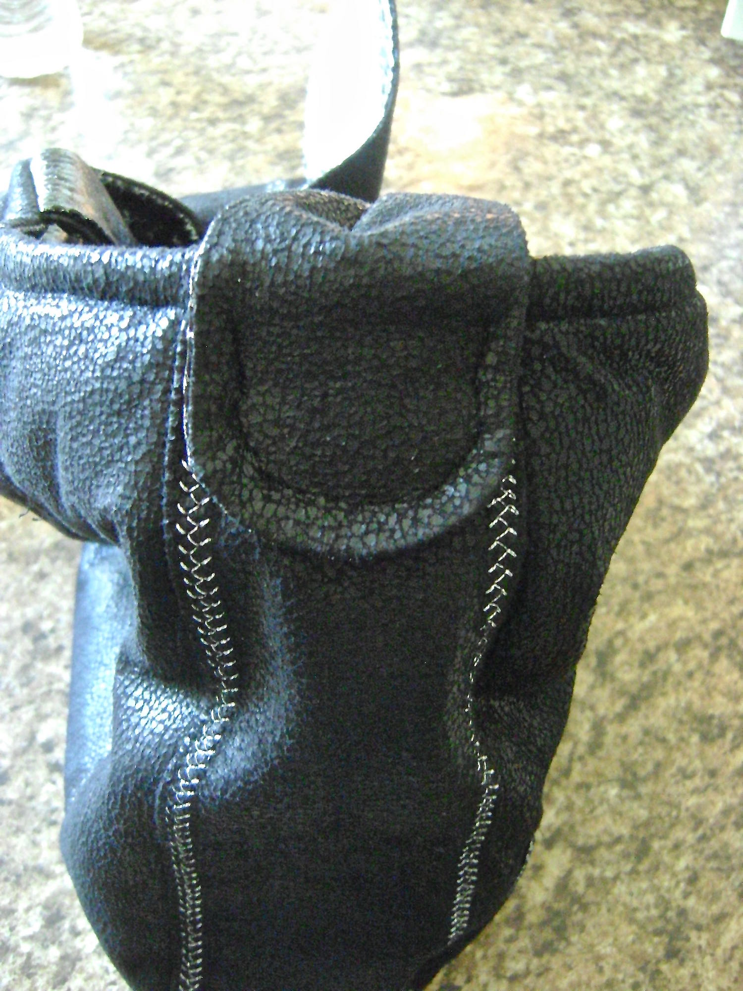 step 29 - Complete the loops by slipping the curved end through the last link in a four link chain. With black thread, sew the curved end to the center side of the purse 1.75” below the purse top edge.