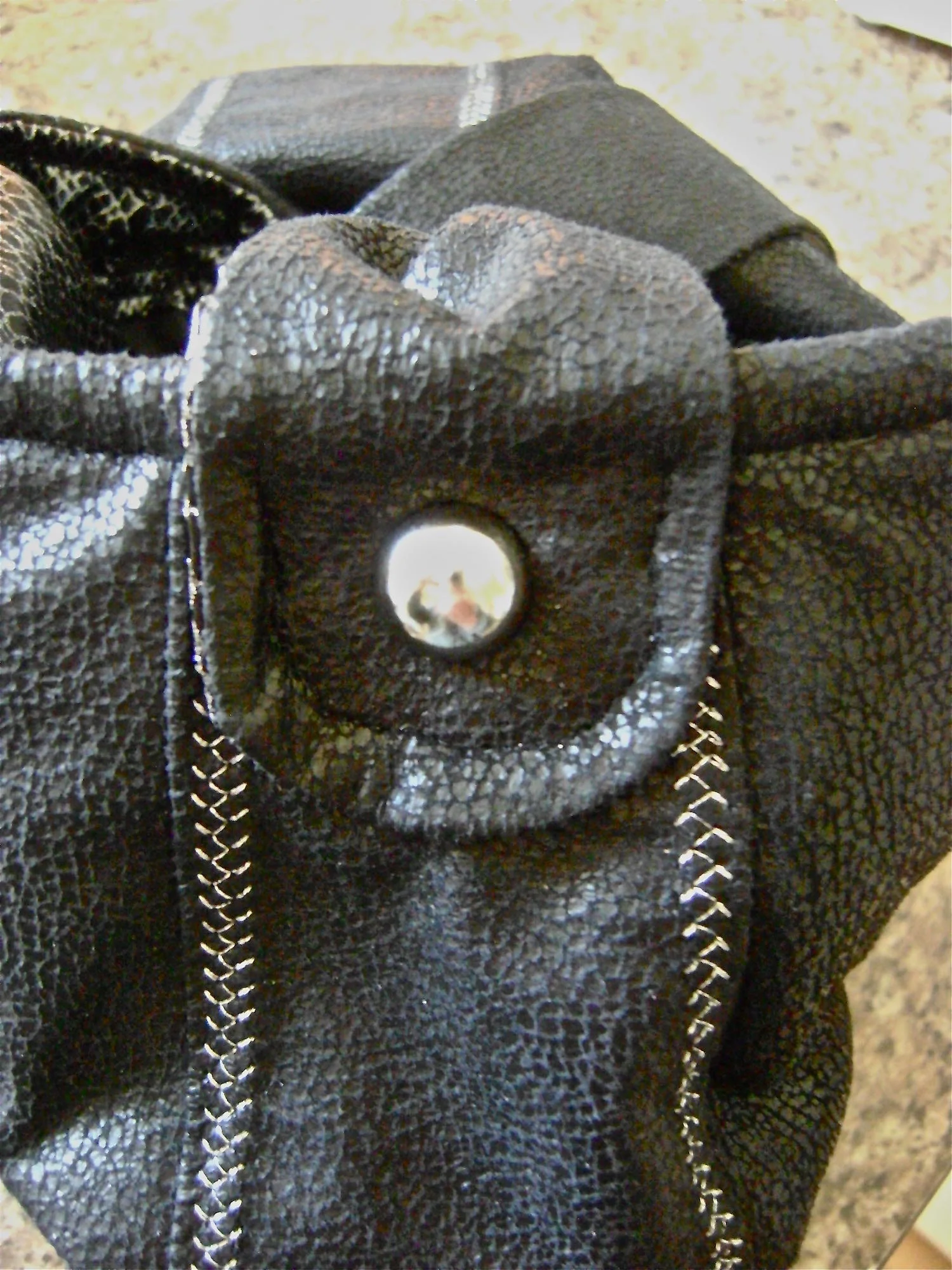 step 30 - Attach a decorative silver stud to the center of the loop. Push the stud through the purse shell and fleece. Attach the back side of the stud between the fleece and the lining.