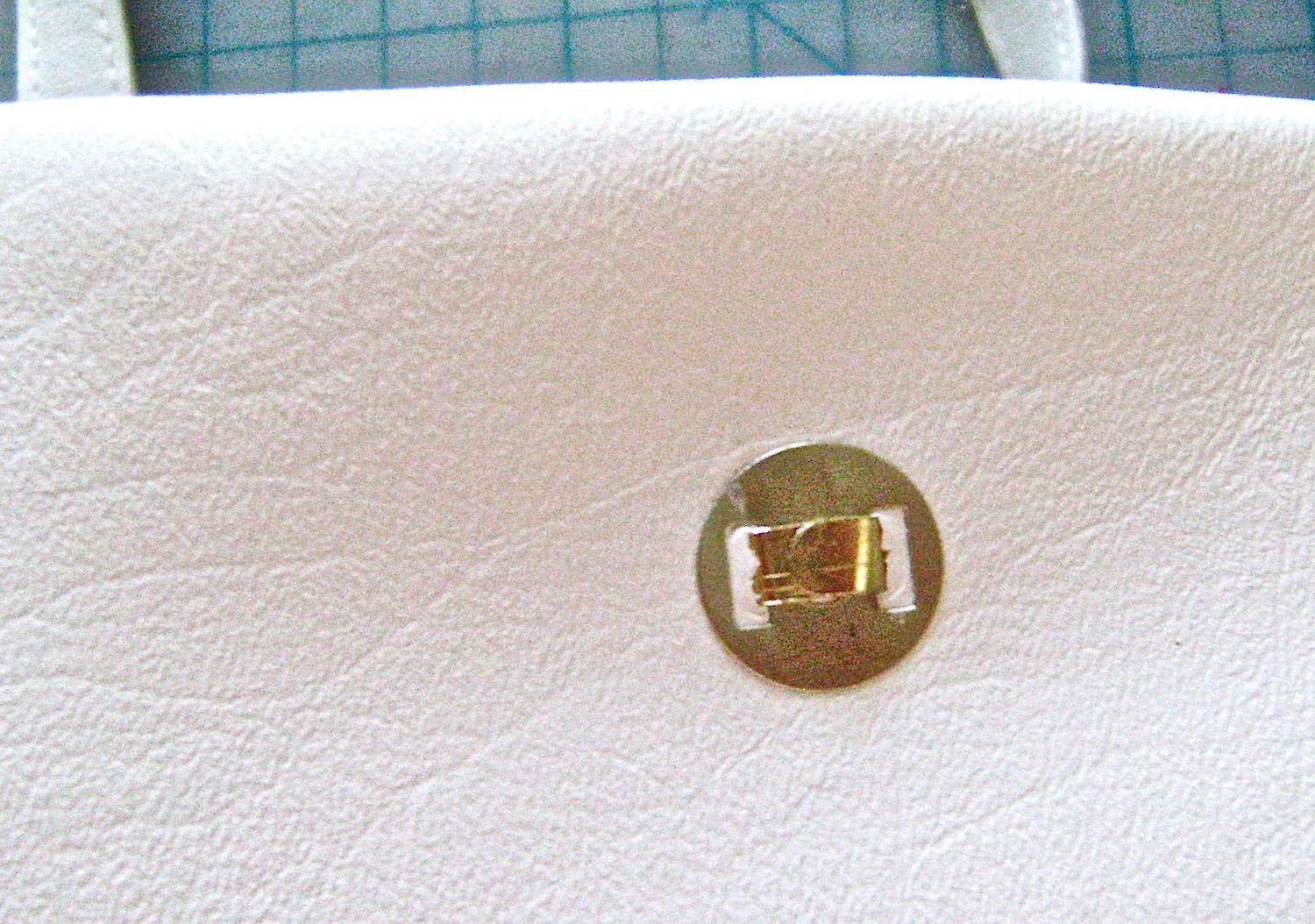step 20 - Attach magnetic clasps to the center of facings on front and back of bag. Push the prongs through the facing and the white vinyl sections with the folded prongs on the outside of the bag.