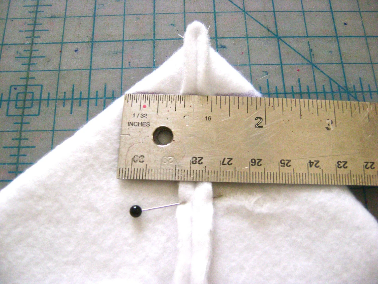 step 16 - Sew the sides of the padding and lining. They are constructed in the same way. Sew the bottom seam leaving a 7” center opening in each. Lay the bottom seam against the side seam of the left and right bottom corners. Pin the seams together to create a triangle. Mark a line across the triangle to measure 2” across. There should be one inch to the left and right of the seam. Sew on the line to create the squared bottom corners of the bag.
