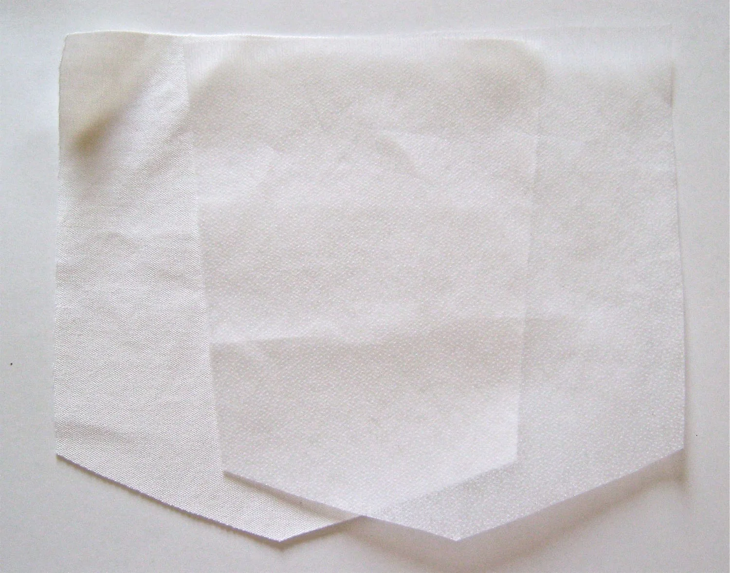 step 1 - Back Pockets Using your pattern pocket piece, cut two from fabric and two from lightweight fusible interfacing. Press the top pocket hem with wrong sides together to create a visible crease.