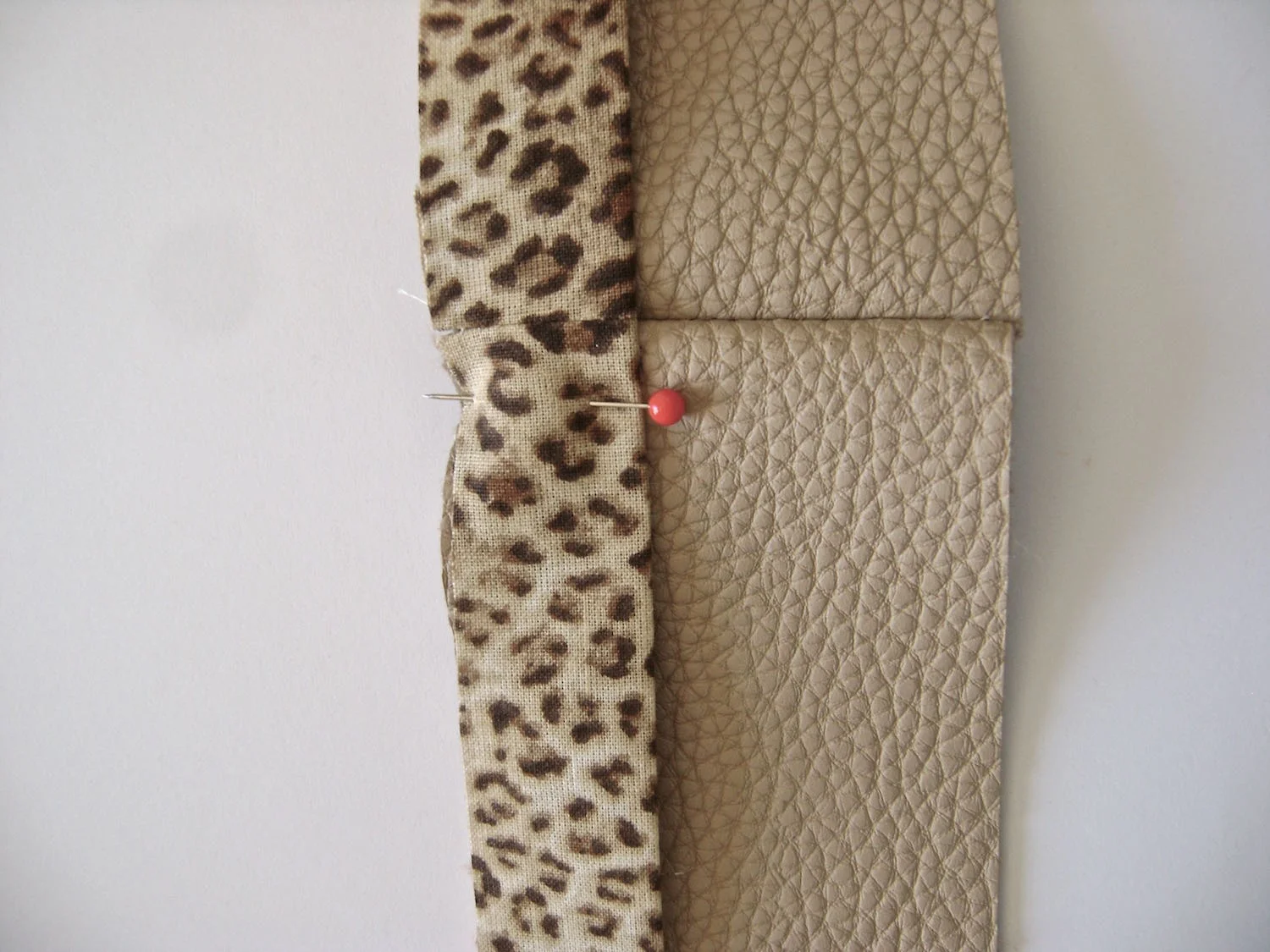 step 27 - Sew the short side edges of the band trim together. Also sew the side edges of both vinyl bands and the fleece bands. Fold the trim in half and sew the raw edge to the edge of a vinyl band. Trim the seam.