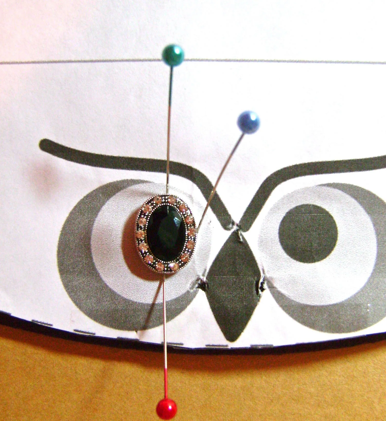 step 12 - Align the pattern piece to the fabric again. Position the center eye bead and border it with pins to mark its placement. Remove the pattern, then the pins.