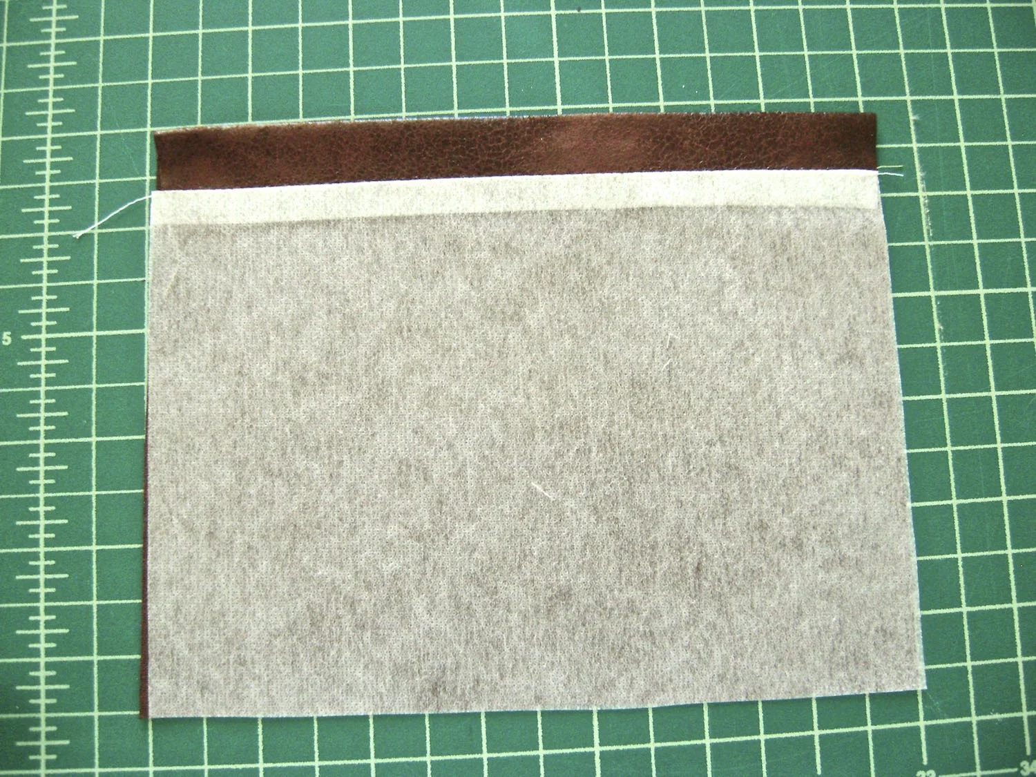 step 16 - Turn the pocket pieces wrong sides together. Create a .50” hem at the top of the pocket. Cut off the .50” excess interfacing and fuse the pocket pieces.