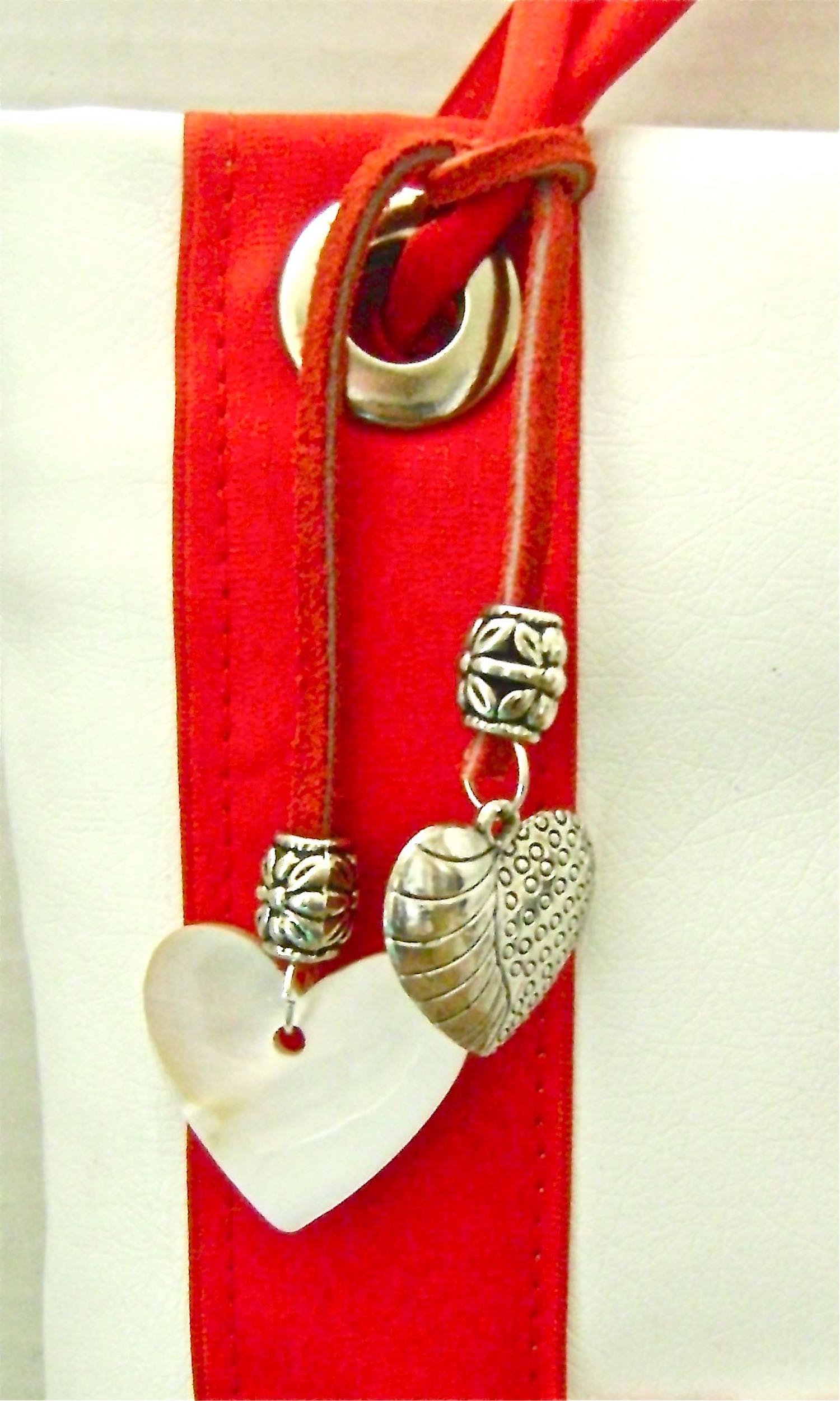 step 19 - Poke holes in the ends of a 7” strip of rawhide cord with a sharp needle. Attach decorative silver beads and attach heart charms with jump rings. Tie the cord around the ribbon.