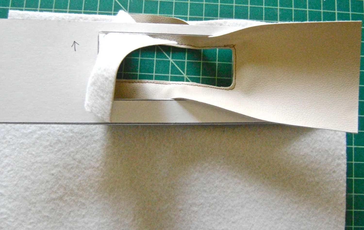step 12 - Lay the cardboard on the wrong side of the vinyl and pull the facing through the hole in the cardboard. Insert Aleene’s Peel n Stick Fabric Fusionsheets between the cardboard and the vinyl pieces to bond them. Place the sheets at least .75” away from edges of vinyl where you will be sewing.