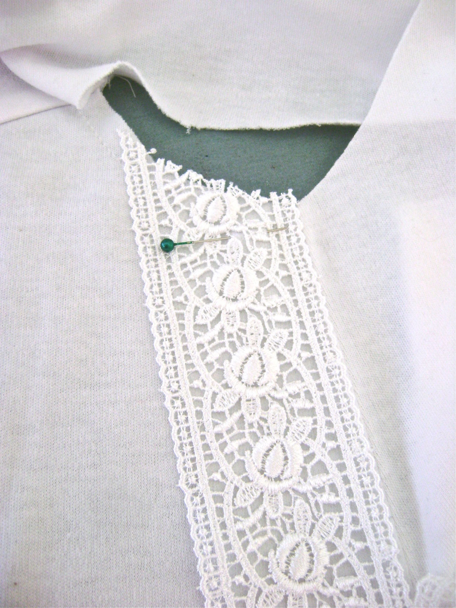step 13 - Position the lace on the shirt front using the center crease as your guide. Open out the facing and pin the lace in place.