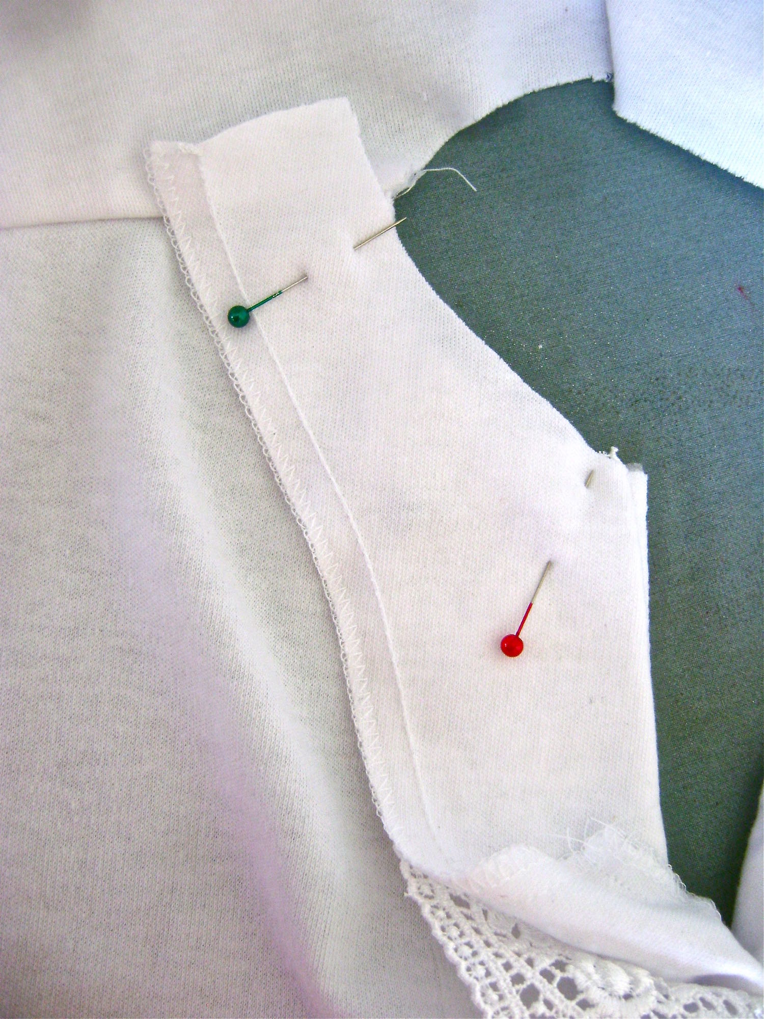 step 14 - Position the right side of the facing over the right side of the lace matching neckline and shoulder edges. Stitch a 5/8” seam from the shoulder seam to the center front neck. Trim the seam. Attach the facing to the other neck edge. Trim the seam. 