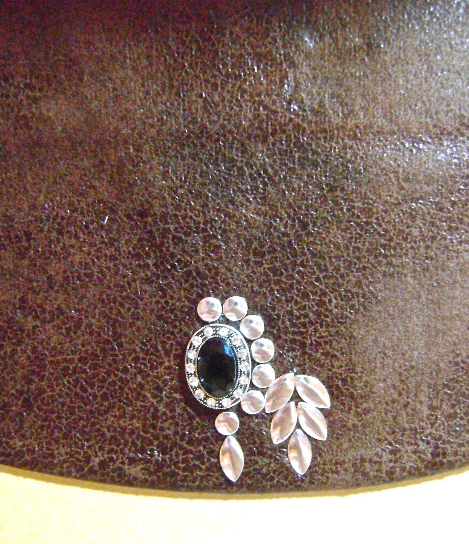 step 13 - Circle the eye with round nail heads. When the circle is complete, follow with the placement of the oval nail heads, including the eyebrow. Cover them with cloth and press with the iron.