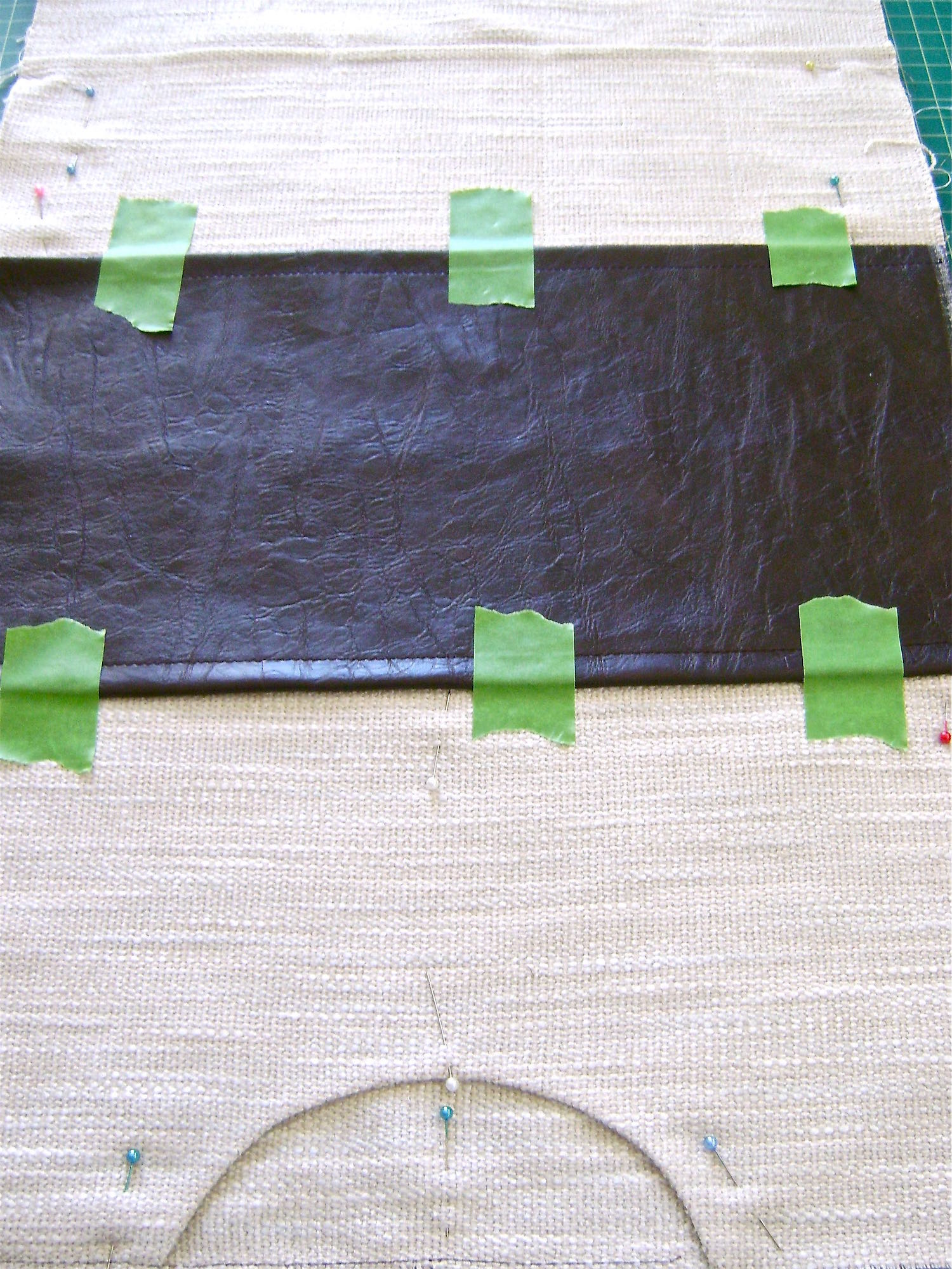 step 4 - Attach The Brown Bottom With right sides together, match the top edges of the front and back of the bag. Cut slits to mark the bottom fold which will be the bottom center of the bag. Fold the brown vinyl for the bottom of the bag with the long ends together and mark or cut slits to indicate the bottom center of the bag. Turn a .25" seam on both long edges of the piece and topstitch at a little less than .25" from the edge. Align the wrong side of the brown vinyl to the right side of the woven fabric matching up the center bottom slits. Sew the brown edges to the woven fabric close to the existing stitch lines.