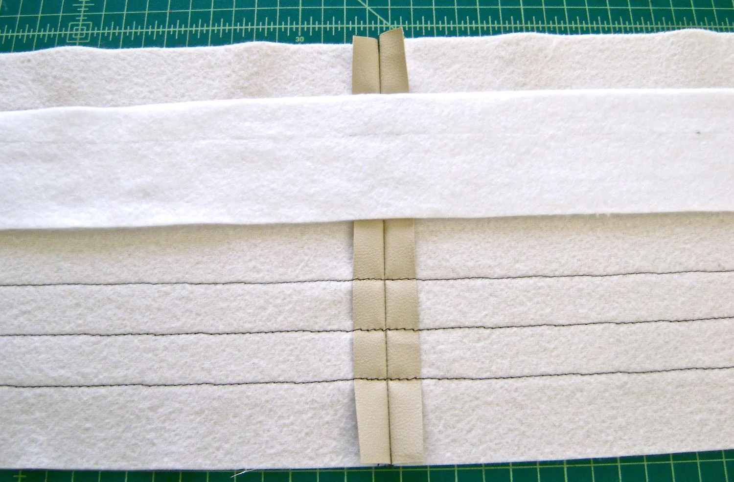 step 6 - Top Band Sew the side seams with right sides together. The decorative top stitching starts one inch from the center of the band when it's folded in half. Use disappearing ink to create five straight lines with a ruler .50” apart on the right side of the front and back pieces. Turn the vinyl to the wrong side and press the fusible interfacing into place. Align the fleece with the top fold line of the band and glue or fuse in several places. Allow to dry.