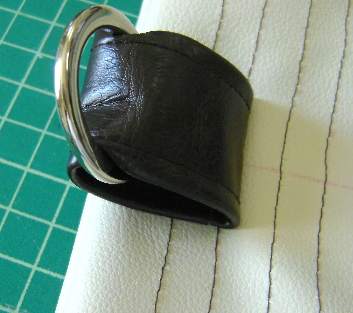 step 12 - Slide a ring onto the tab. Turn the tab with the right side facing the right side of the band, tucking the end against the trimmed edge. Sew the tab across the first stitching line of the band. Sew in a rectangle moving across the bottom edge and ending where you started. Repeat for all four tabs.