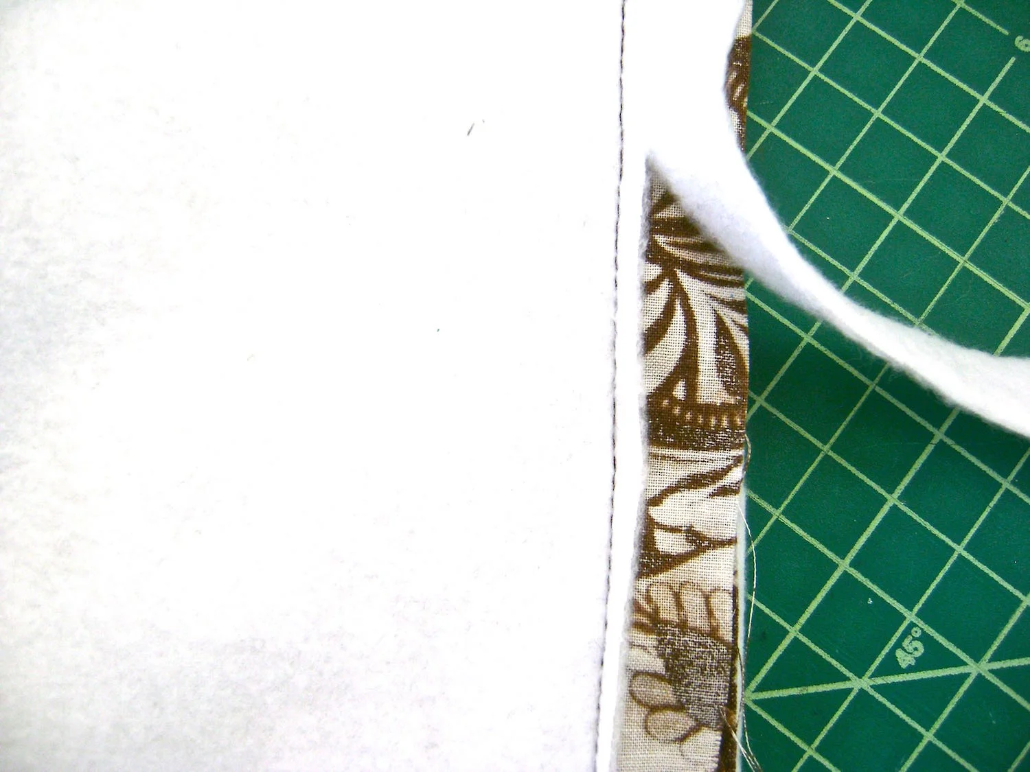 step 14 - Lining and Fleece Padding Add zippered or open pockets to the front and back lining pieces as desired. Sew the side seams of the lining and fleece. Sew across the bottoms, three inches in from the sides. Leave the middle sections open. Sew the four inch corners as you did with the woven fabric. Sew the fleece to the wrong side of the lining in a 75" seam at the top edge. Trim the fleece close to the stitching. Place the cardboard into the bottom of the bag fitting it into the corners. Slip the bag into the lining right sides together. Sew the lining to the the bag with a normal 5/8” seam. Machine or slip stitch the bottom center of the fleece followed by the lining. Push the lining and fleece into the bag.