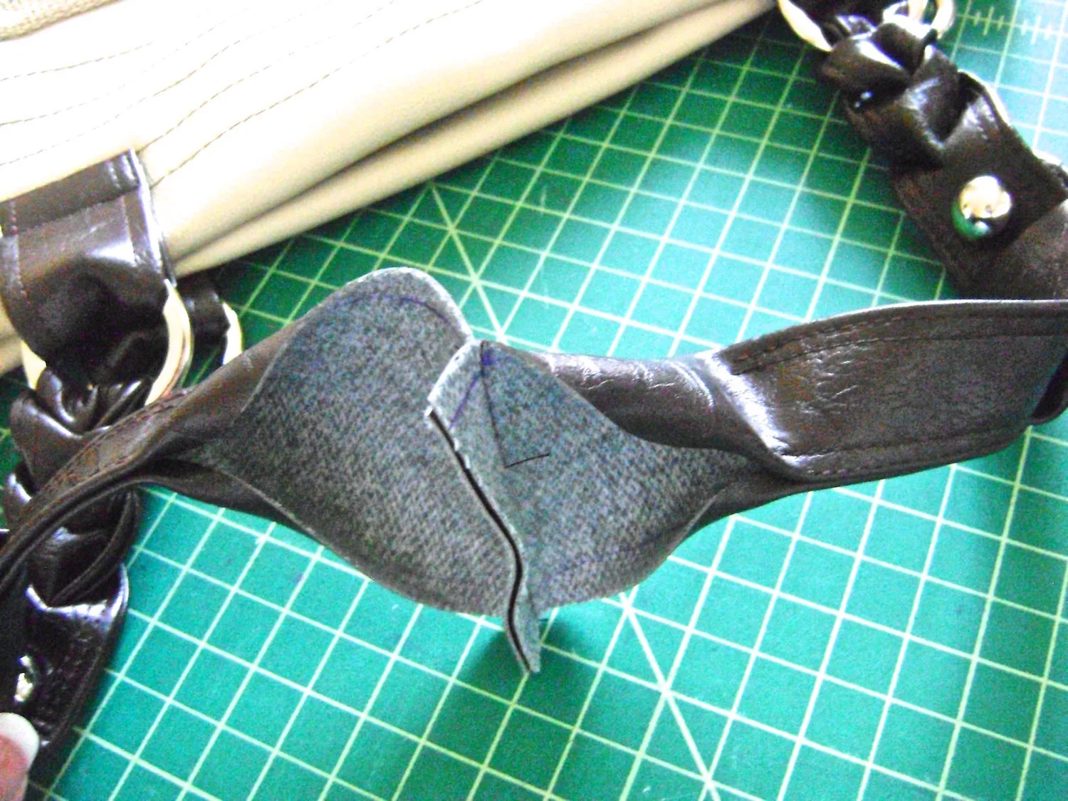 step 20 - With right sides together, sew each set of straps with a .50” seam to create one long strap on the the front and one on the back of the bag. Turn the edges .50” to finish hemming the strap with top stitching. Add a .25” brad to teach of the strap tabs.