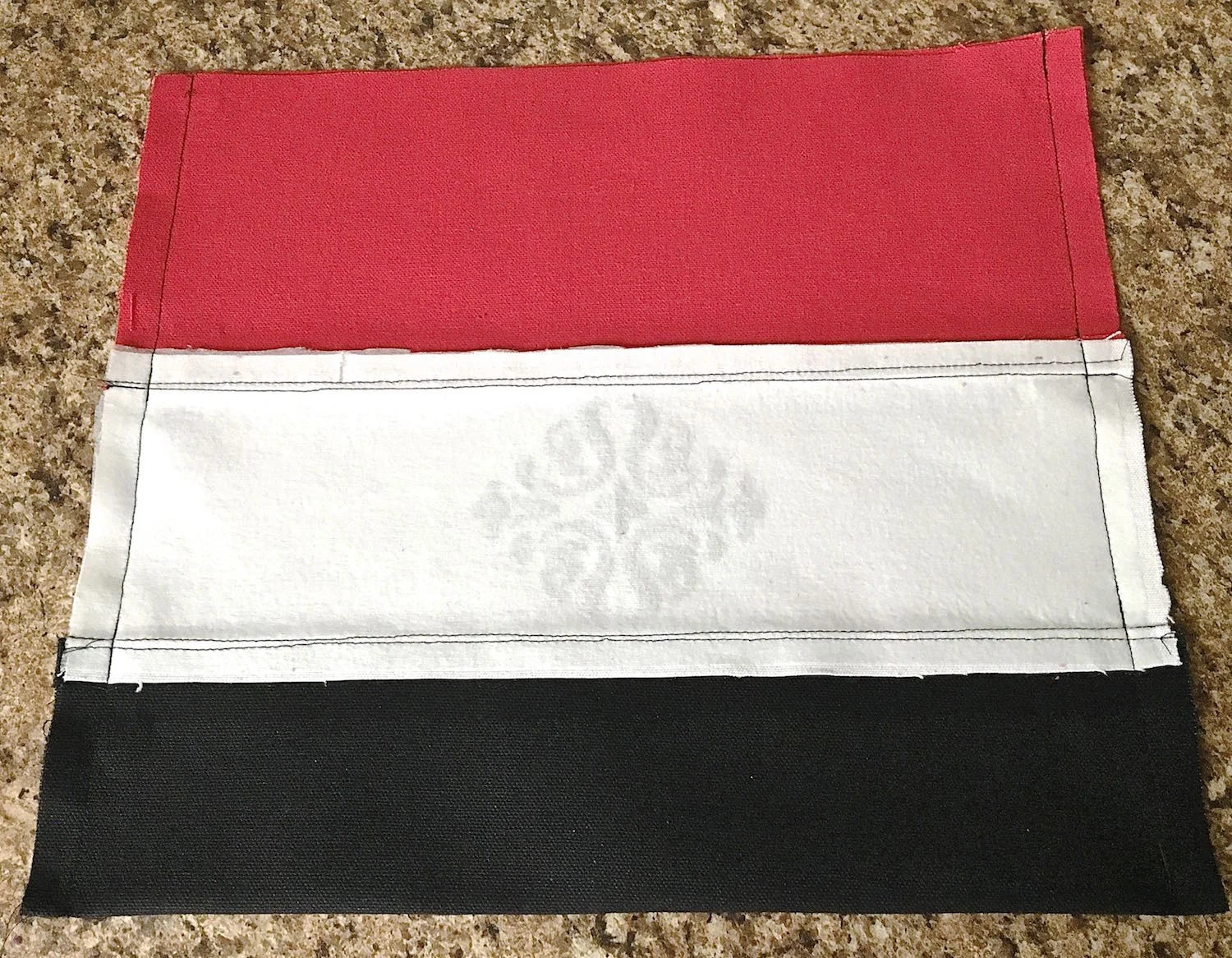 step 6 - Fold the fabric in half matching the top red edges with right sides facing. Pin together. Sew the side seams from the red panel down to the black panel.