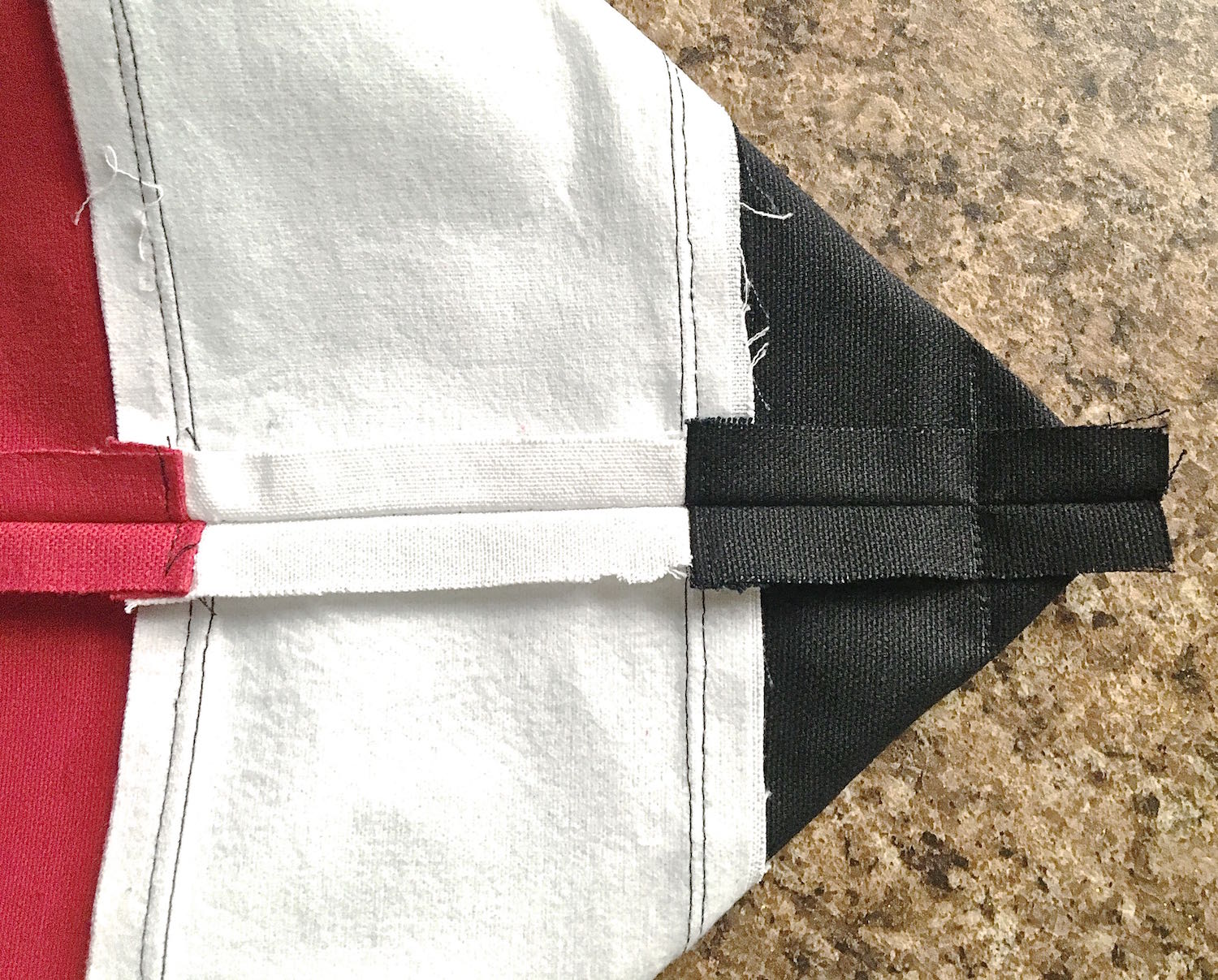 step 7 - Facing To create the bag bottom, align the side seam with the center bottom of the bag and press it flat with your hands. Draw a line across the fabric2” from the point. There should be 1” to the left and right of the seam. Stitch across the line. Repeat this on the other side of the bag.
