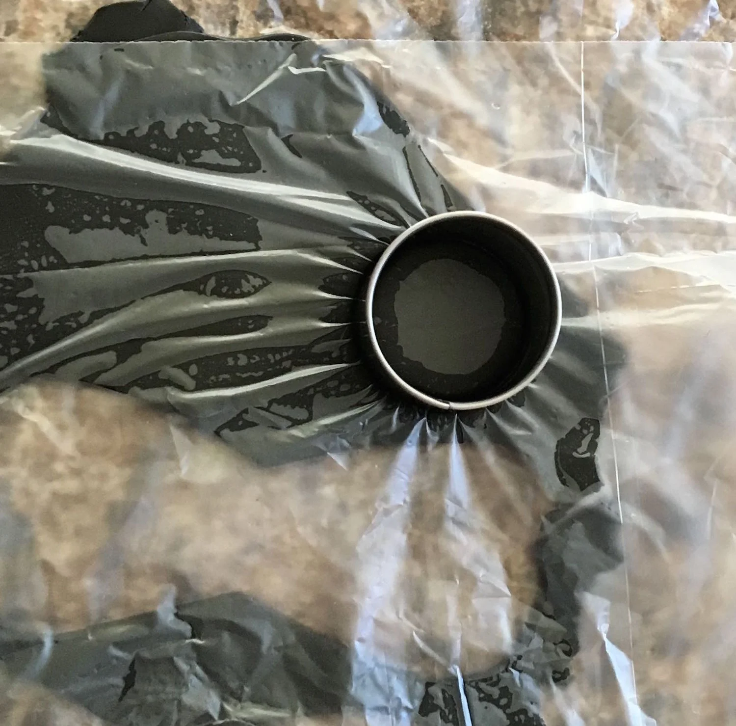 step 26 - Place plastic wrap over black clay rolled on #2 setting of a clay conditioning machine or flatten clay to 1/8” thick. Use a .75” round cutter to create four discs.
