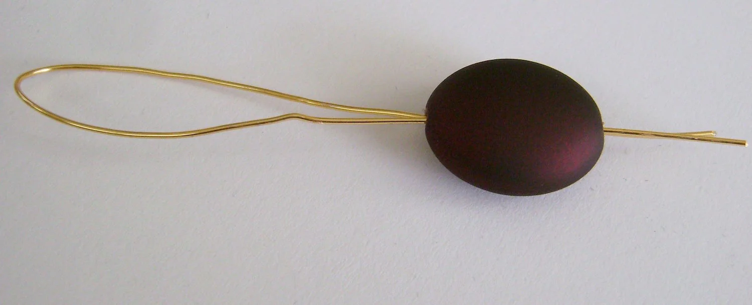 step 1 - Cut a piece of 18 gauge gold wire 8” long. Fold in half and insert the two ends into the bead. 