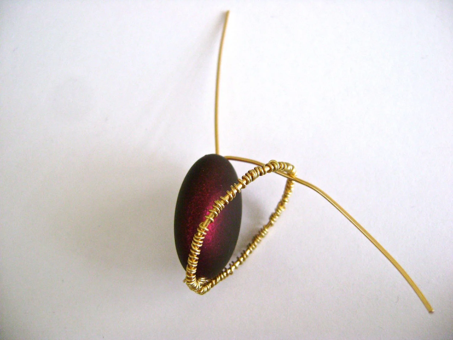 step 8 - Insert one of the stems under the wire-wrapped oval and push the oval up to surround the bead.
