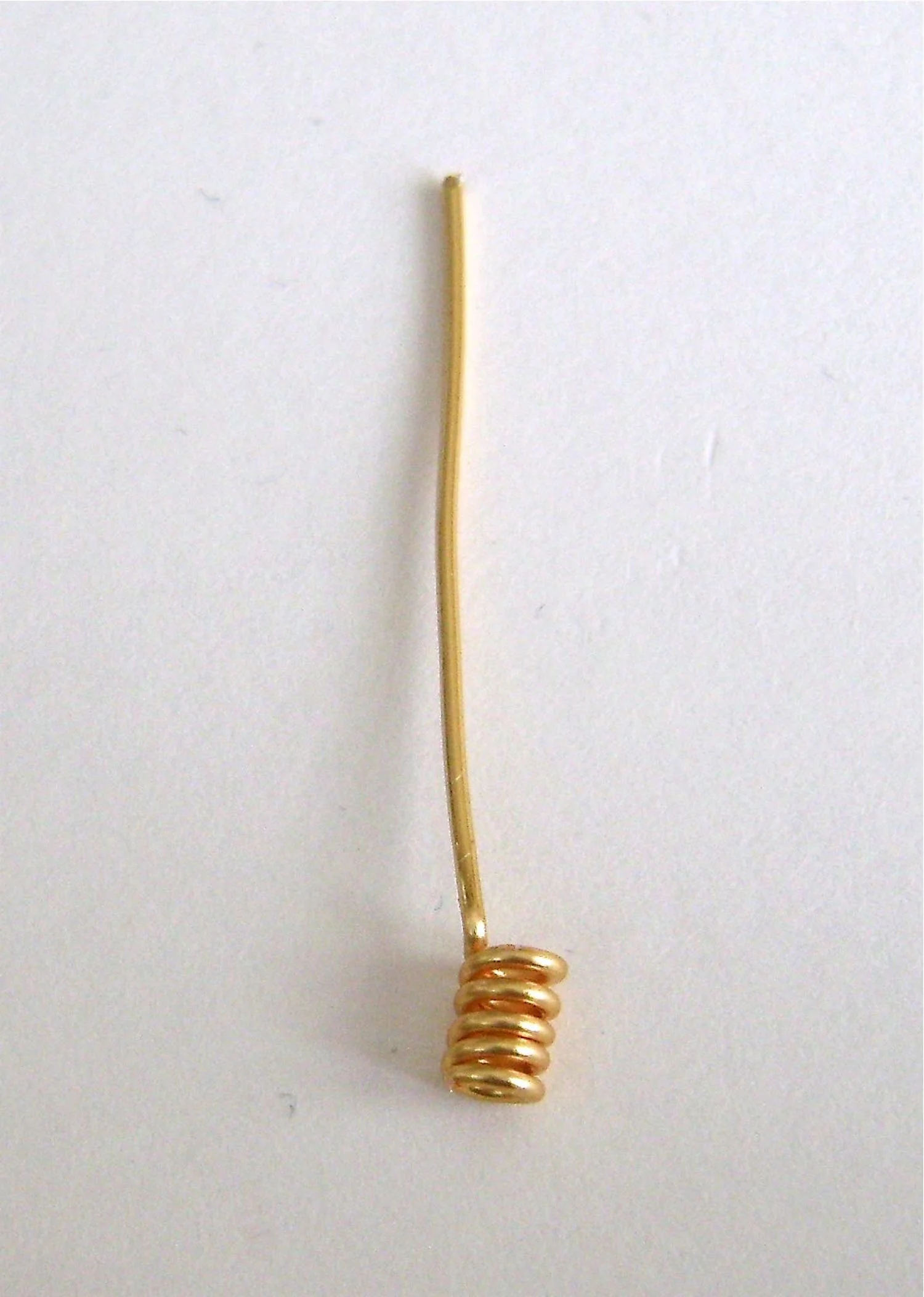 step 10 - Wrap a small length of 18 gauge wire around a thin round object, like a fine knitting needle, four times. Slip the coil off the object. Bend the excess into a 90 degree angle. Leave a 1.25 tail and trim the ends.