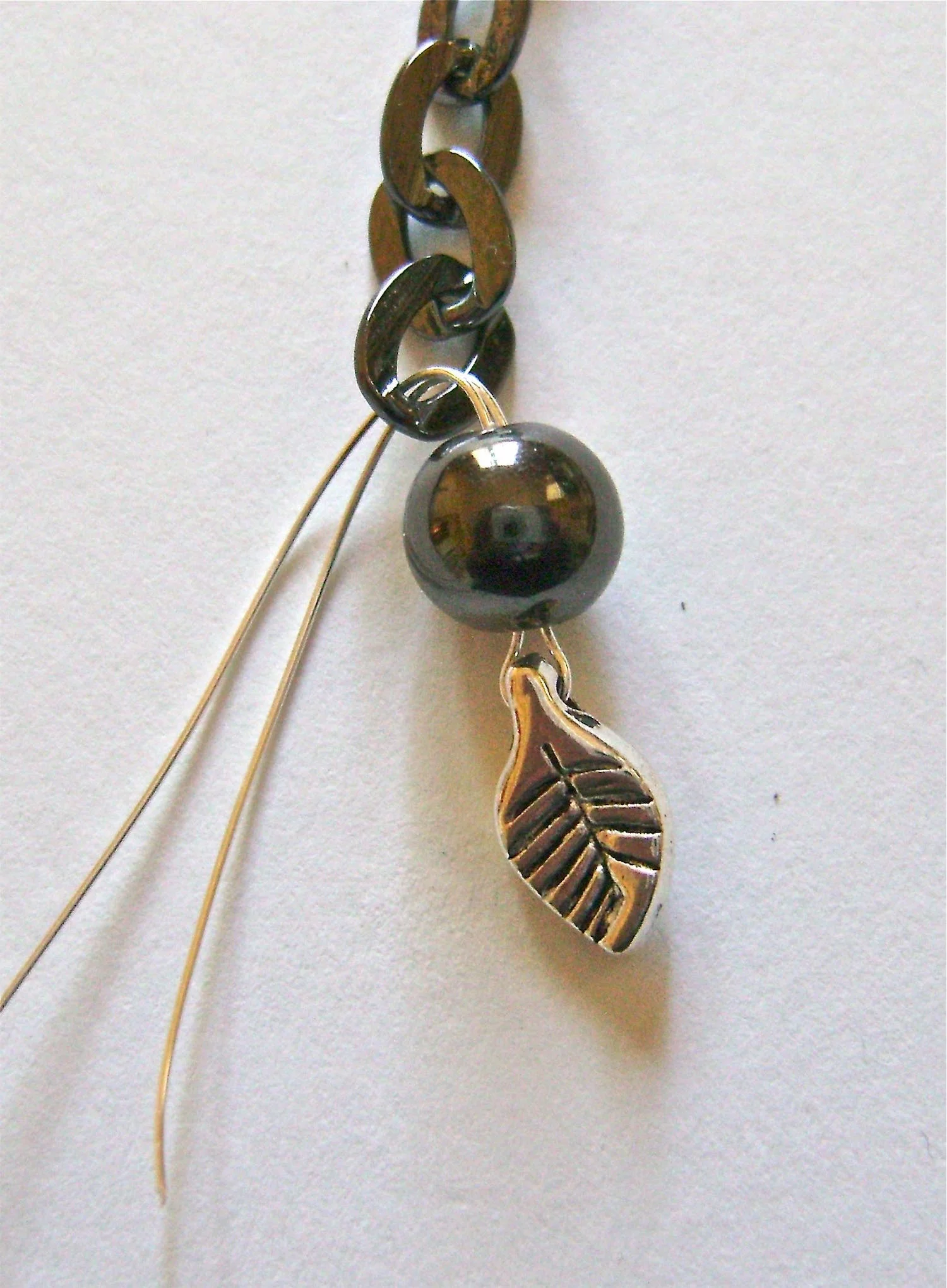step 4 - Create a chain section by threading the wire ends into a six link piece of the black chain. Bend the wires down toward the leaf.