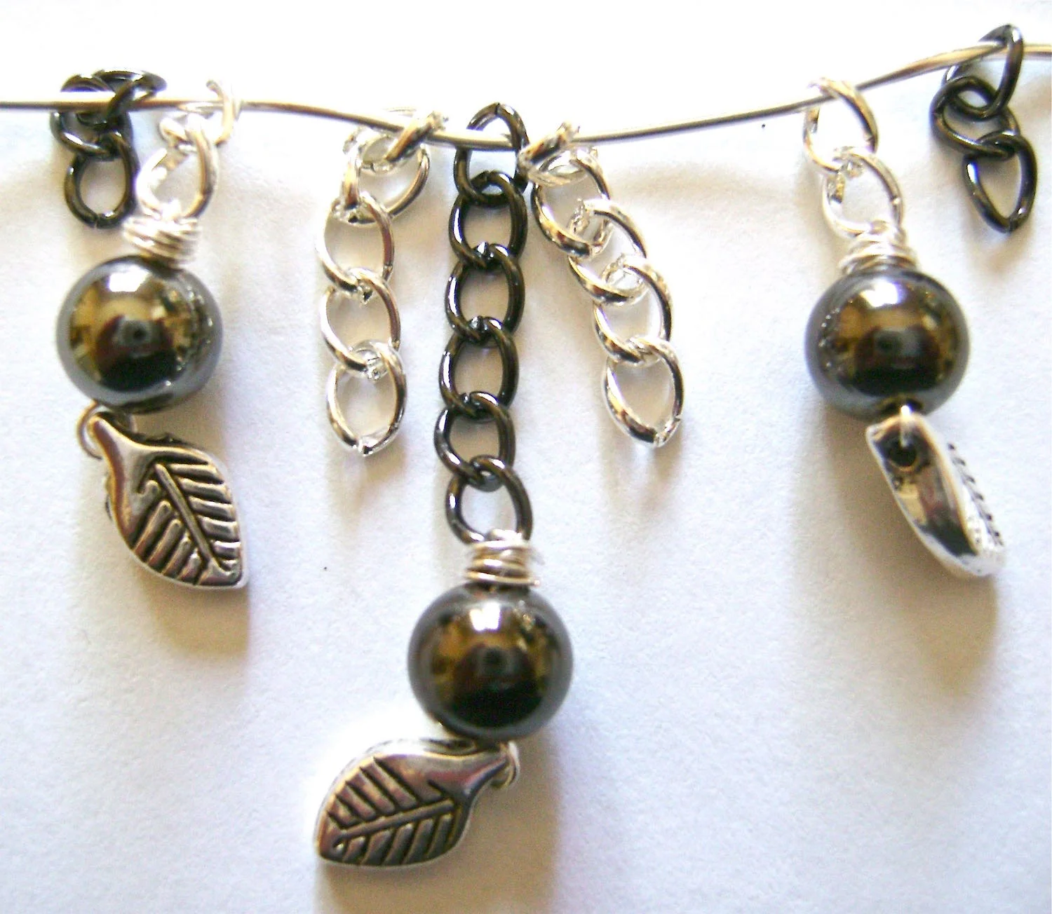 step 8 - Each earring is made up of the chain sections pictured. They should be in the following order: 3-link black, 2-link silver, 5-link silver, 6-link black, 5-link silver, 2-link silver, 3-link black. Note that every other chain piece is just chain with no attachments. (sections are strung on wire for display purposes only)