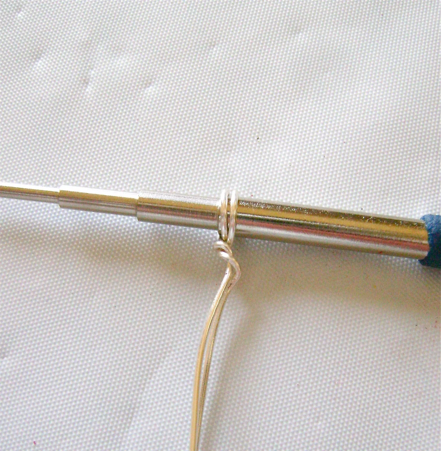 step 2 - Grab the wire stems with flat nose pliers and twist the ring tool to wrap the wires around each other.