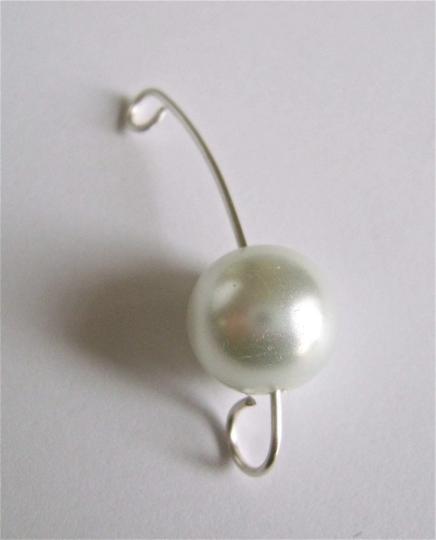 step 3 - Cut another length of wire to measure 2” and curve it to match the previous wire. Create a curl on one end to match the other curls. Slip on a pearl. With the small end of the round nose pliers, make a curl in the top of the wire.