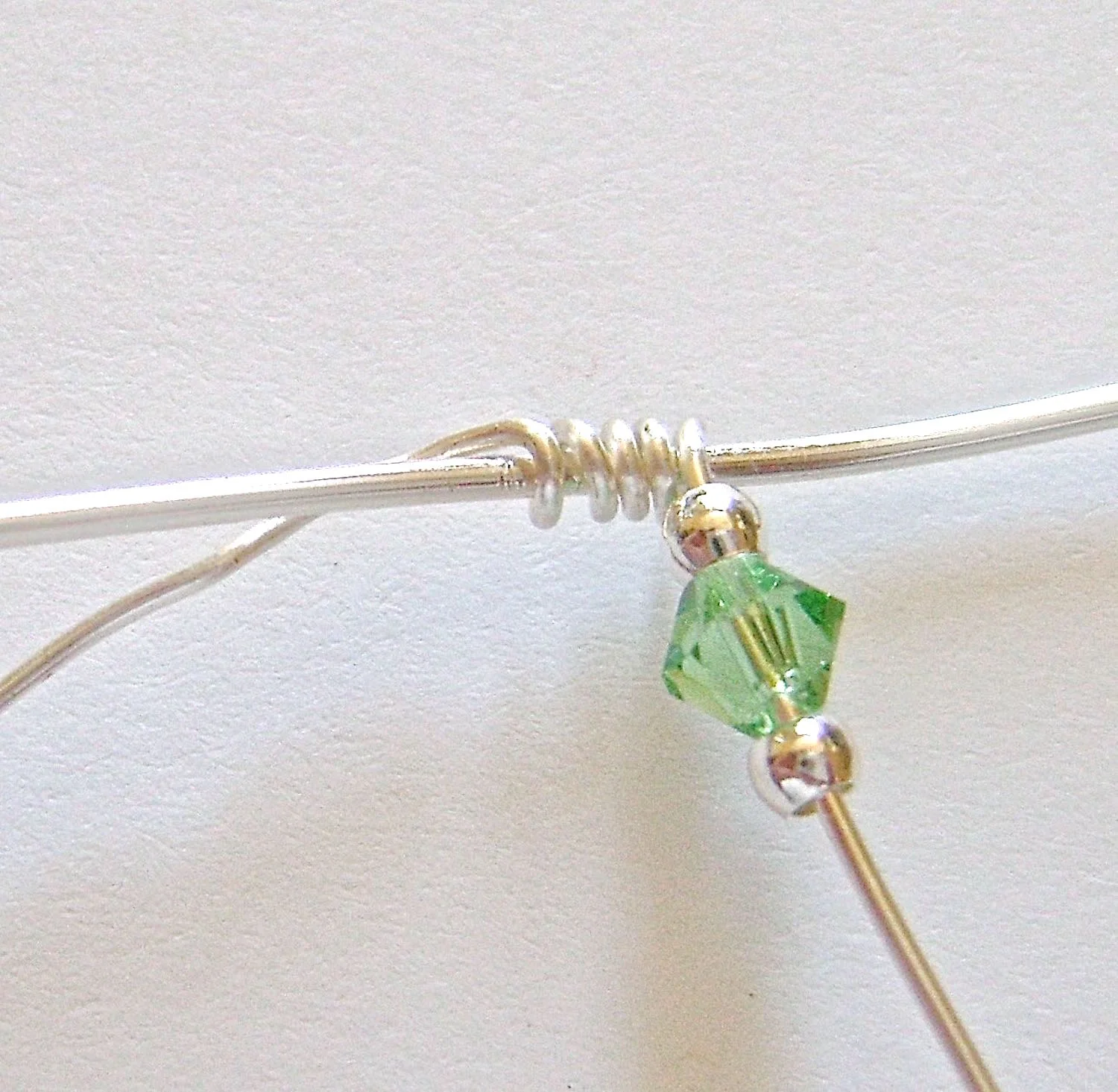 step 3 - Add a silver bead, bicone, and another silver bead to the right side wrapping wire.