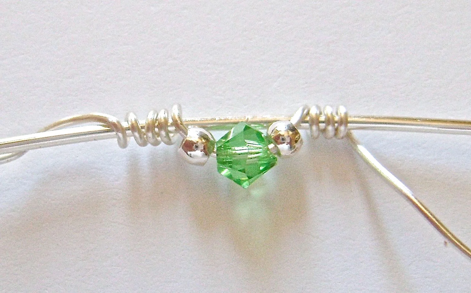 step 4 - Hold the beads against the wire to keep them from moving and wrap the free end around the 5” wire four times.