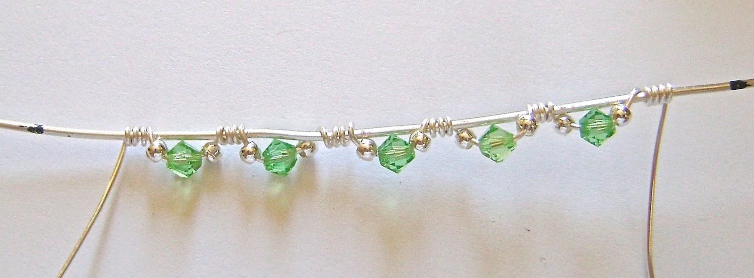 step 5 - Continue wrapping and adding beads until you have three sets attached to the 5” wire. Do the same with the left side wrapping wire adding only two sets for a total of five sets.
