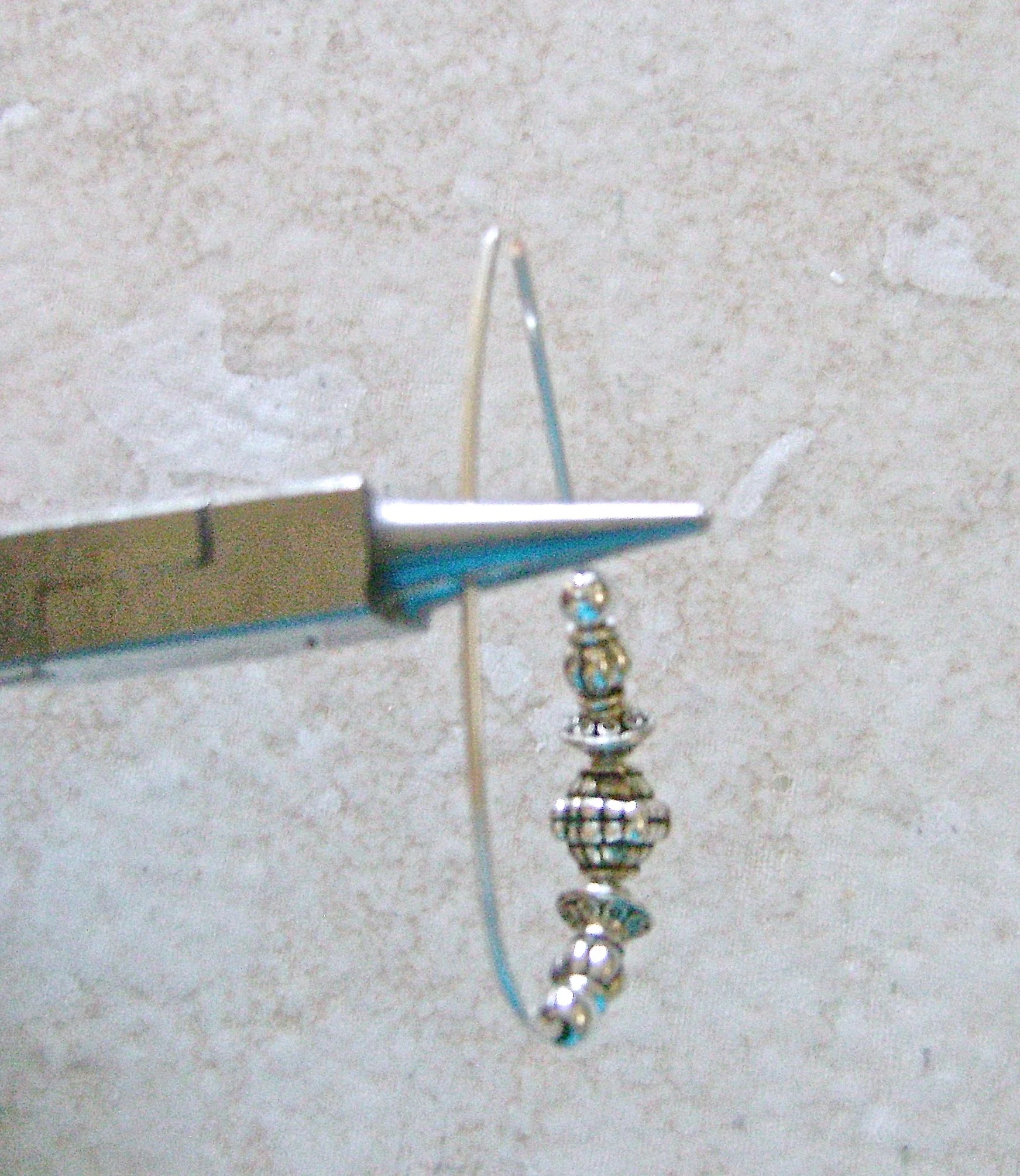 step 4 - Grasp the wire at the mark with the wide part of the round nose pliers. Wrap the wire around the pliers to form a complete loop.