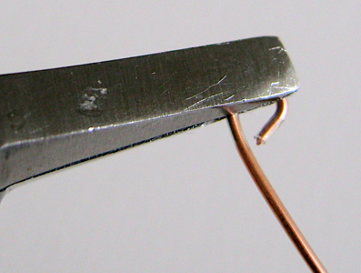 step 2 - Form a spiral by firmly grasping the loop you created with flat nose pliers.