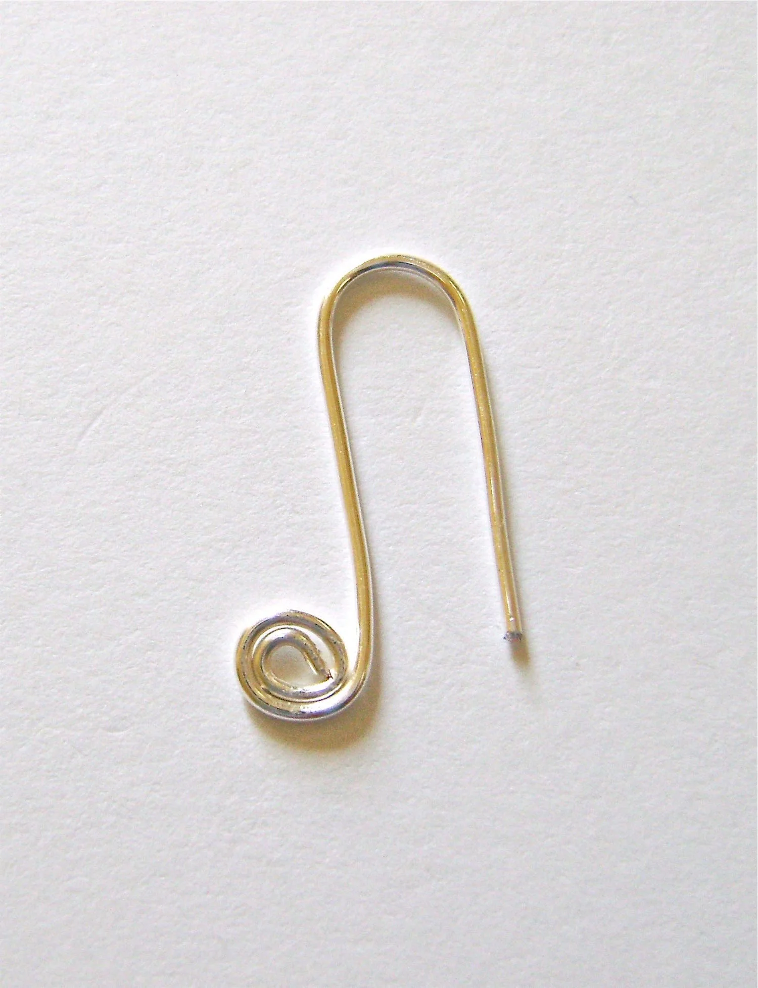 step 4 - Smooth the wire over a pencil or other round shape to create a curved bend. The straight end of wire shouldbe aligned horizontally with the the top of the spiral. Create a spiral with the straight end.