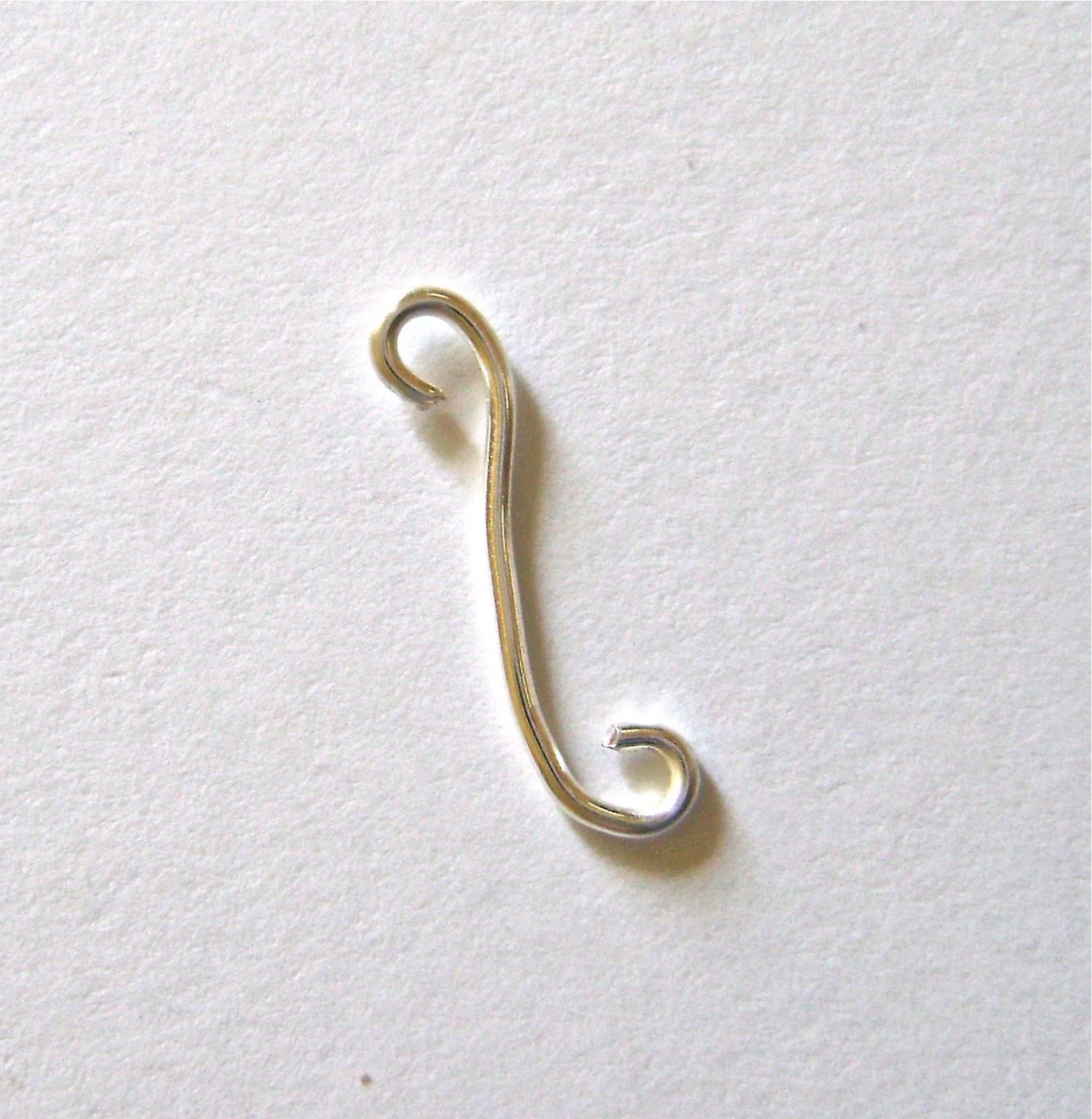 step 5 - With a new piece of wire and the round nose pliers create open loops on each end. Curve it into a reverse “s” shape with your hands. The curve piece should be about 2/3 the length of the main wire.