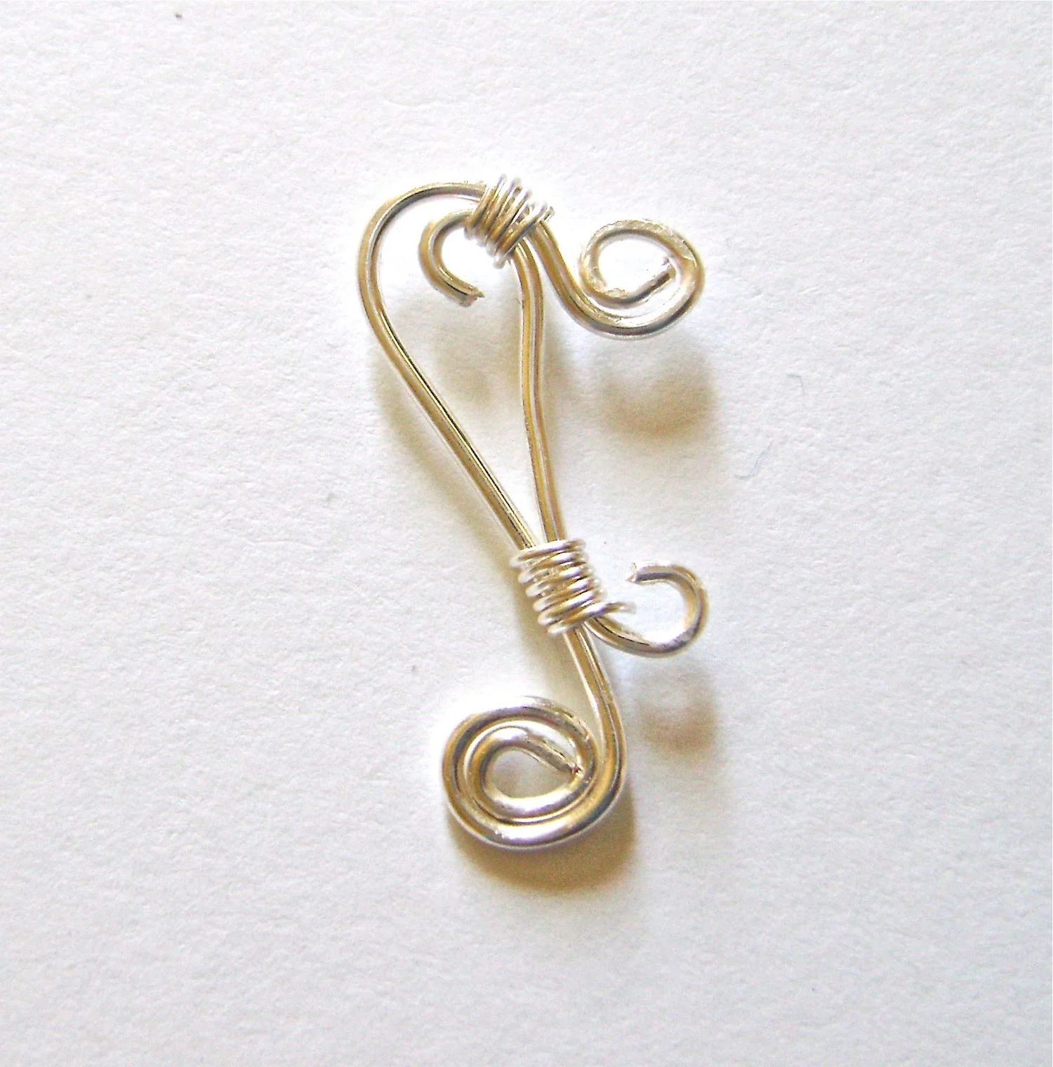 step 7 - Join the “s” to main wire by wrapping 24 gauge wire around them about 5 times. Do this at the top of the pieces and bottom as shown. Snip off the excess wire. Use needle nose pliers to flatten the cut ends against the work to avoid sharp edges.