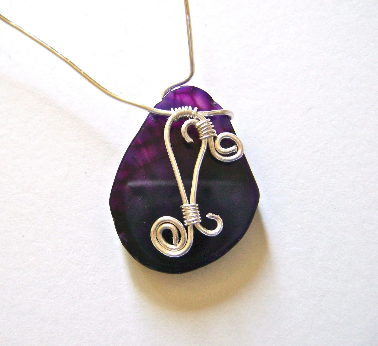 step 11 - Slide the scrolled wire piece along the long wire to the center of the stone.