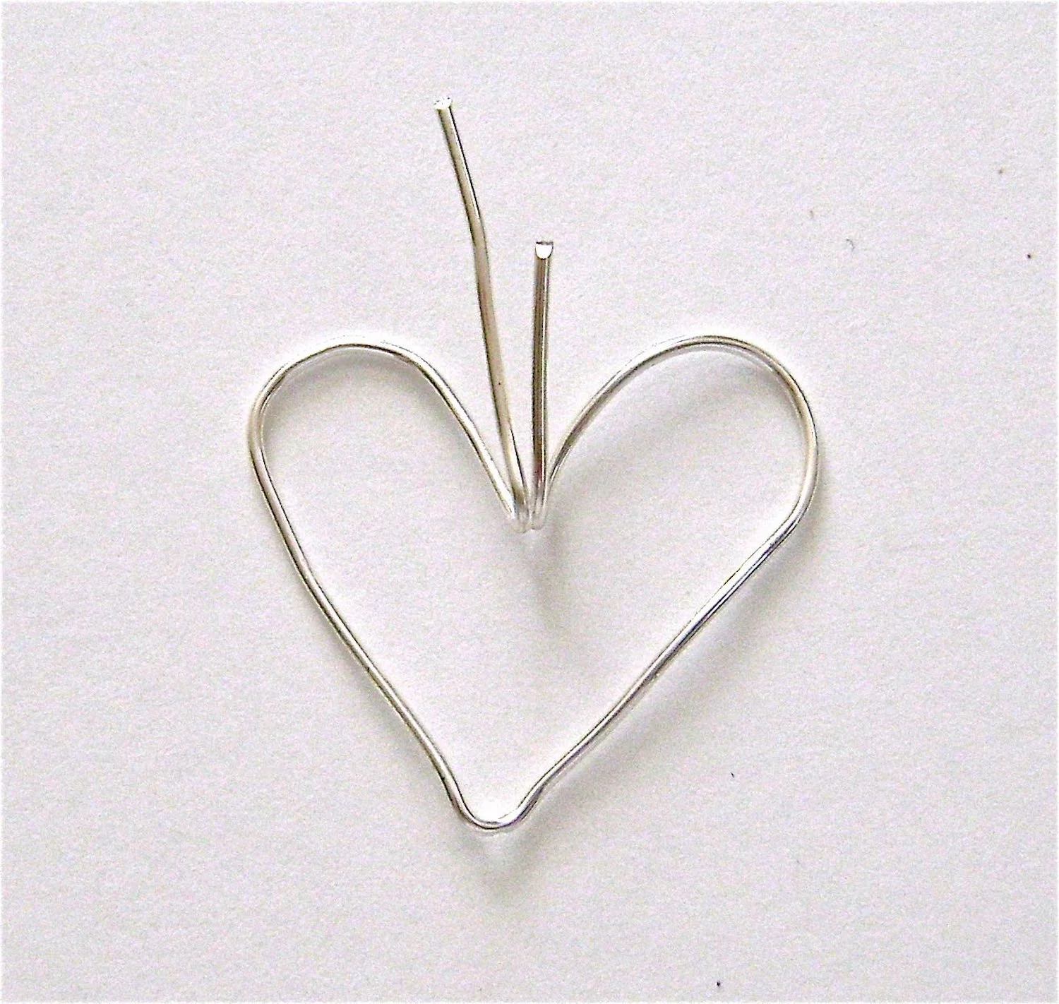 step 3 - Bend both wires to an angle where they meet in the center. The edge of a metal ruler is ideal for this. Create a 45 degree angle with the wires pointing up from the heart. These wires will form the pendant loop later.