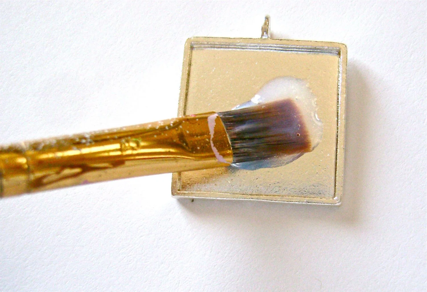 step 2 - Fill a small container with Diamond Glaze. Using a brush, apply a light coat of glaze to the inside of the pendant frame. Be sure to get into the corners.