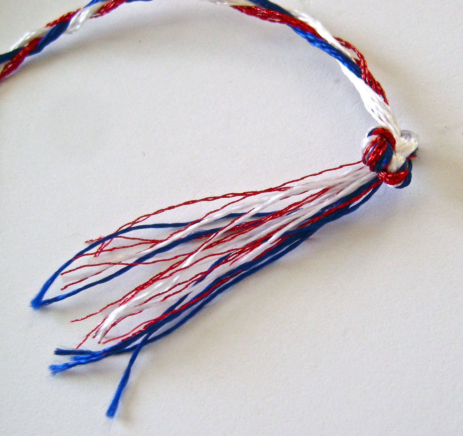 step 8 - Tie two more knots on top of each existing one creating one thick knot on each end of the braid.