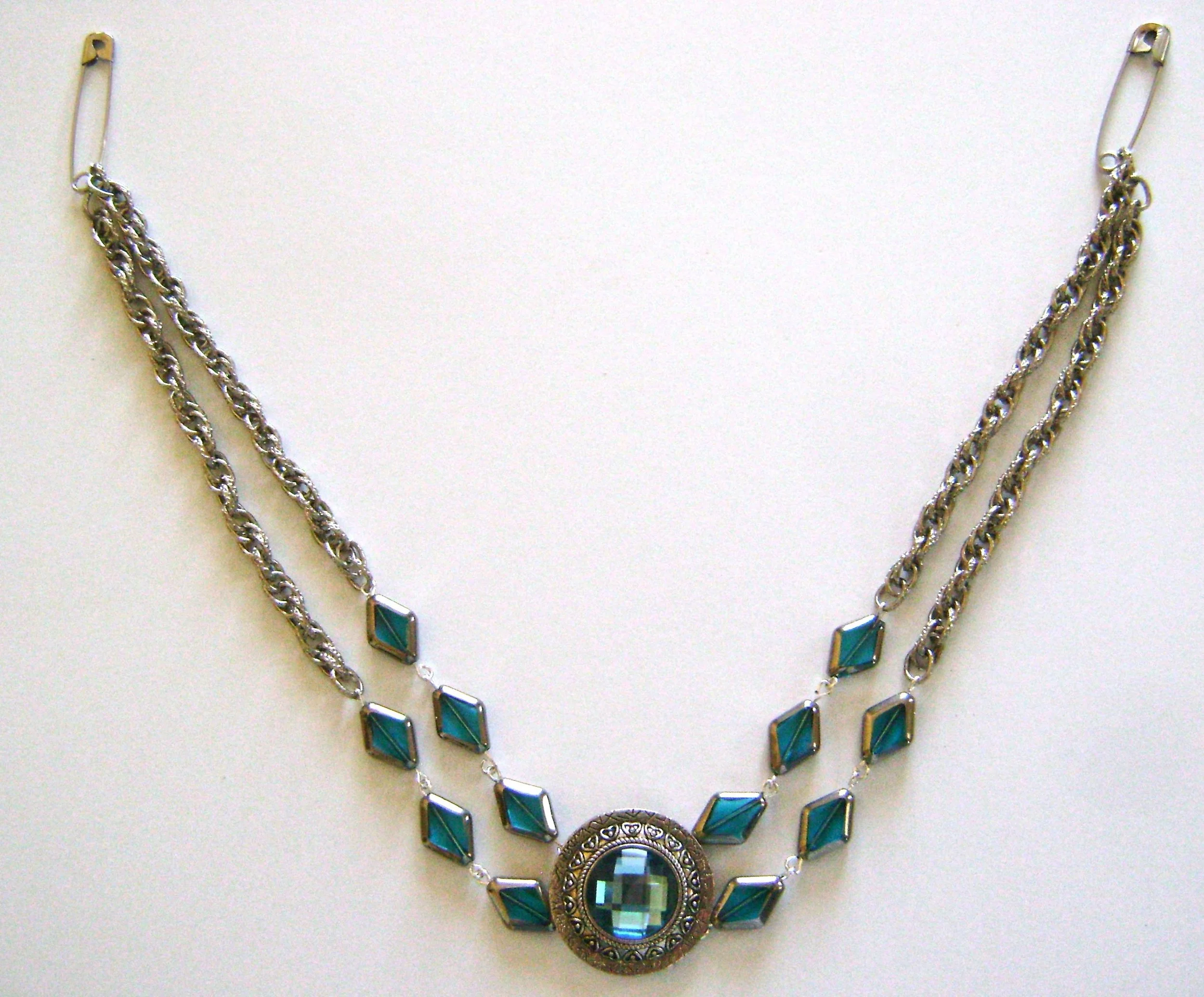 step 6 - In order for the necklace to hang evenly, one strand must be slightly shorter than the other. An easy way to determine where to attach the clasp is to hook safety pins through the chain. Try the necklace on and keep moving the safety pin until one set of strands hangs lower than the other to curve evenly at the neck.