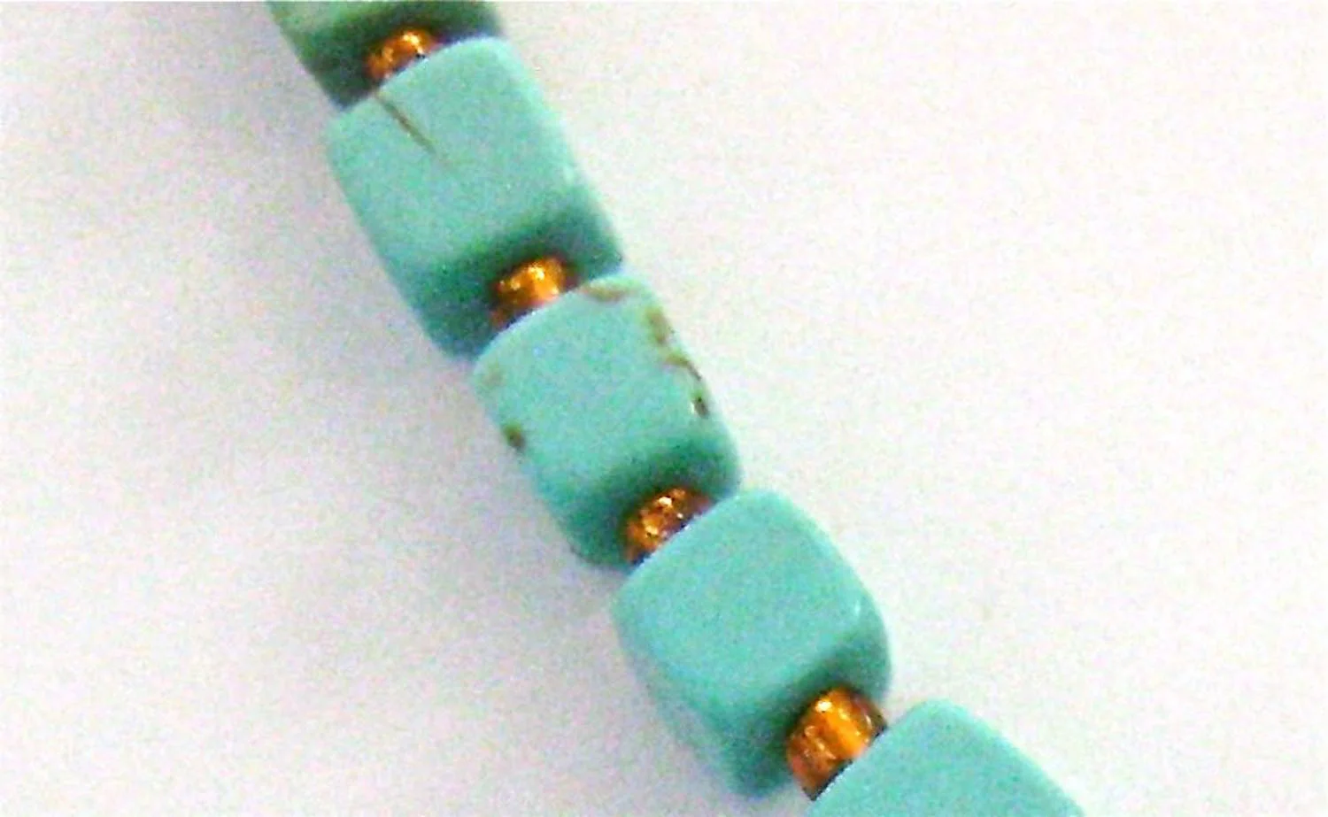 step 8 - String 30 cube beads onto the beading wire separating each with a seed bead. Put the wire through the two copper jump rings. Add a seed bead and 30 more cube beads separated by seed beads.