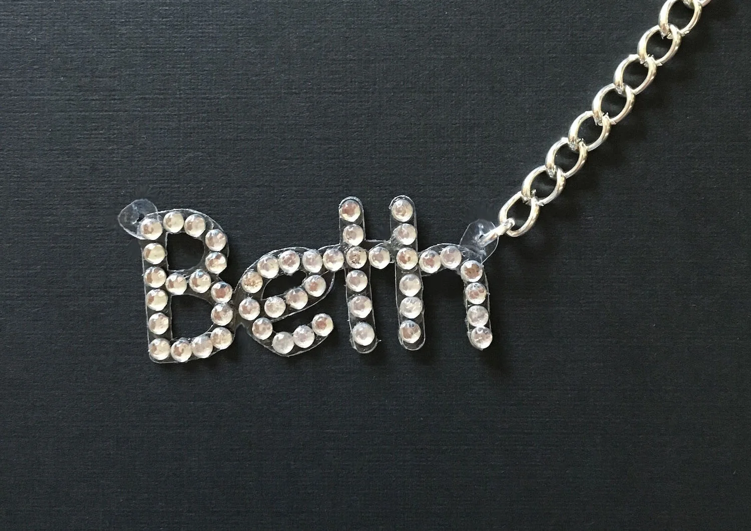 step 10 - Insert jump rings into the tabs and attach a chain to each with jewelry pliers. The two chain lengths may need to be different depending on the height of the first and last letters you use. 
