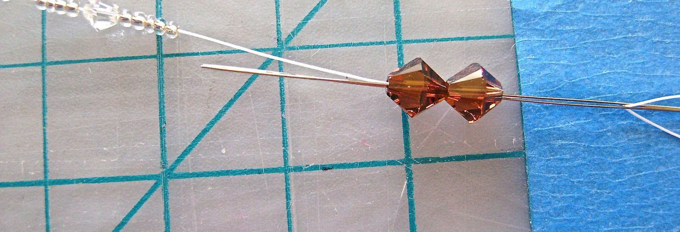 step 2 - Thread on 5 seed beads, a 4MM bead, then 5 more seed beads. Put the needle through the two 6MM beads working from right to left.