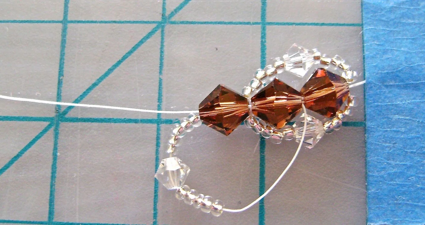 step 7 - Once again, thread on 5 seed beads, a 4MM bead, then 5 more seed beads. Put the needle through two 6MM beads, the new one and the one behind it. Pull through. Complete the second set by adding 5 seed beads, a 4MM bead and 5 more seed beads. Again, put the needle through two 6MM beads and pull through. You now have two complete sets. You will add one 6MM bead and continue to work the rest of your bracelet in the same way.